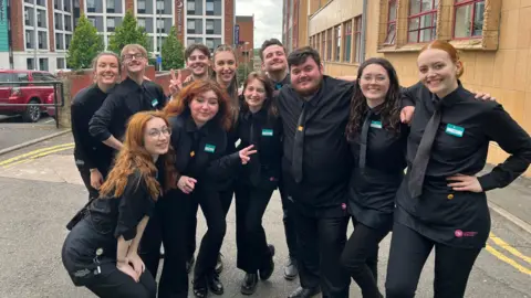 Theatre staff in all black posing outside as a group